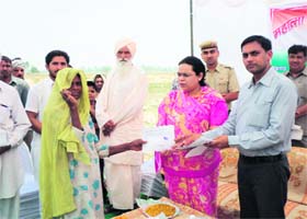 A woman of Deodkheri village in Kaithal receives the allotment letter for a 100 square yard plot from Deputy Commissioner Amneet P Kumar