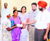 Kahan Singh Pannu, Deputy Commissioner, hands over a cheque to a widow in Amritsar on Friday.