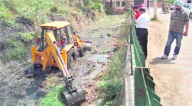 A JCB machine cleans a drain near the Choice Resort road in Baltana on Friday.