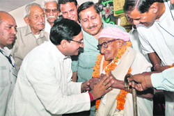 Chief Minister Ramesh Pokhriyal Nishank honours Dula Devi Gusai, widow of an ex-serviceman, at a sammelan of the BJP in Dehradun on Sunday. 