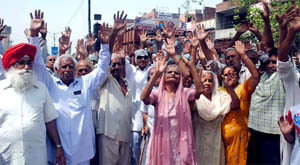 Pensioners block Faridabad-Sohna road to protest delay in the making of pension cards in Faridabad on Monday.