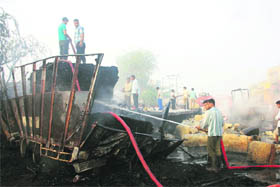 A man tries to douse a fire which broke out after a collision between two trucks near Silana village in Jhajjar district on Monday. 