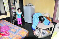 A woman tries to save her belongings as rainwater enters her home following rain in the Karanpur area of Dehradun on Friday.