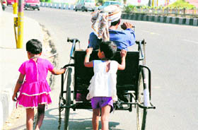 These little girls assist their father while moving on an elevated road in Jammu.