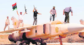 Libyan rebels stand atop a fighter plane belonging to forces of Muammar Gaddafi at Misrata airport on Saturday.