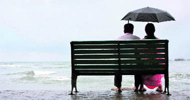 A couple rests on a seaside promenade during a shower in Kochi on Sunday.