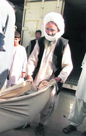 Afghan locals carry the body of a child, killed in a NATO air strike, at a hospital in Lashkar Gah in Helmand province on Sunday. 
