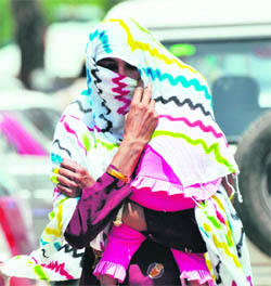 A woman tries to protect her child from heat wave as temperature crosses 40 degree Celcius in Gurgaon. 