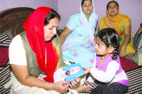 An inconsolable Narinder Kour, along with her daughter, holds a photograph of her husband Vikram Singh at their home at Ramgarh, near Jammu, on Wednesday