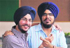 Amanjot Singh (right) and Amandeep Singh offer sweets to each other to celebrate their success.