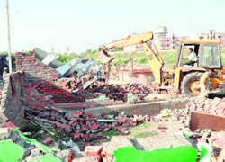 A bulldozer of the MC demolishes illegal structures at Ram Nagar on Friday.