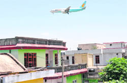 An aircraft flies above the densely populated Gadi Garh locality just before landing at the Jammu airport
