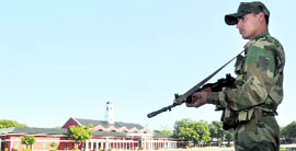 An Army man stands guard at the Indian Military Academy in Dehradun where the passing-out parade will be attended by the President .