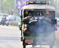 An overloaded auto-rickshaw billows out toxic fumes. 