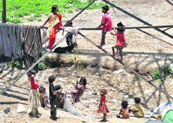 Children of jhuggi dwellers play at the base of a high-tension power transmission tower on the Bindal river bed in Dehradun