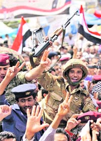 A Yemeni soldier along with anti-government protesters celebrate Salehs departure, in Sanaa on Sunday