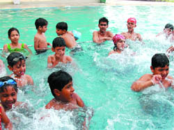 Children beat the heat by splashing about in a swimming pool at a summer camp organised in Bathinda