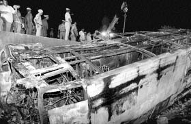 Policemen stand near the bus that plunged down a bridge and caught fire near Kaveripakkam, about 100 km from Chennai, on Tuesday midnight. Twenty three persons were killed in the mishap