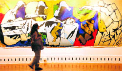 A file picture of a visitor taking a look at a huge painting, titled Pieta, by MF Hussain at an exhibition in Mumbai