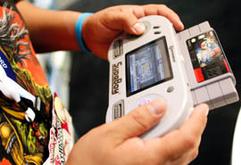 A gamer plays with Hyperkins SupaBoy portable gaming device which plays original SNES game cartridges during the Electronic Entertainment Expo or E3 held in Los Angeles on June 8, 2011. 