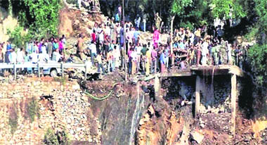 Villagers stand near the rubble of a landslide triggered by a cloudburst at Baggar in Doda, on Friday