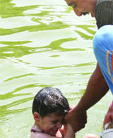 A child enjoys bath at a pond near India Gate on a hot day in New Delhi 