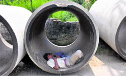 A boy takes a nap in a cement pipe in Jammu on Sunday