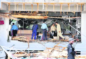 Pakistani security officials examine a damaged bank building after a suicide bomb attack in Islamabad on Monday