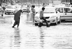 In troubled waters Pedestrians and vehicles struggle to negotiage a flooded Patiala highway following rain at Zirakpur