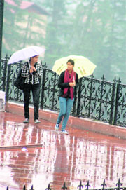 Girls take cover under umbrellas during rain in Shimla on Friday. 