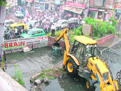 MC workers try to clear a clogged drain near the ganda nullah; and (right) cars in the MC parking were submerged following heavy rain in Ludhiana 