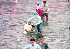 People wade through knee-deep water near the Damoria Bridge in Ludhiana