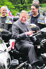 Britain's Prince Charles laughs as he sits on a motorbike during a reception for members and supporters of the Royal British Legion Riders Branch in London on Friday
