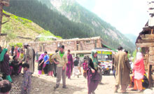 People gather outside a polling booth after casting their vote at Choorwan village in the Gurez sector on Saturday.