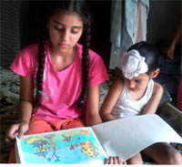 Harmeet Kaur who has a hole in her heart showing her paintings while her brother looks on