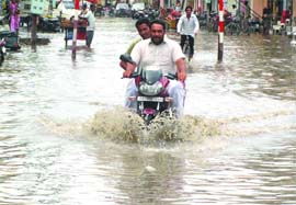 knee-deep in trouble: A motorcyclist wades through accumulated rainwater in Sirki Bazaar in Bathinda on Monday.