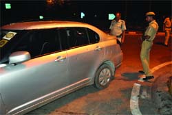 Policemen inspect the car of a businessman who was shot at  in New Delhi on Sunday night