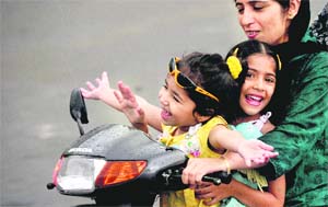 Children enjoy a ride in the rain with their mother on a scooter in Ludhiana on Monday. 