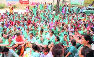 Health workers of the Civil Hospital sit on a dharna in Ludhiana on Monday.