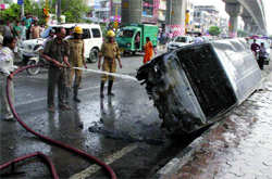 Firemen spray water on a car that caught fire in New Delhi on Wednesday
