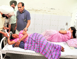 Two women share a bed in the maternity ward of the Ludhiana Civil Hospital even as the Civil Surgeon, Dr HS Bali (extreme left), disburses cheques to patients on Thursday