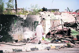 An elderly Libyan man walks past damaged houses in Tripoli Street in the Libyan port city of Misrata on Thursday as Libyan leader Muammar Gaddafi said he did not fear death and defiantly vowed to fight to the beyond. 