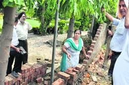 Sarla Bhatia constructs the wall of her sister's farmhouse despite opposition from the workers of a developer in Ludhiana on Friday