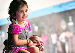 A man carries his little girl on his shoulders as she enjoys the rain at the Ludhiana Railway Station on Sunday