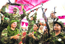 Women supporters of Libyan leader Muammar Gaddafi wear army fatigues and hold up weapons as they attend a women's forum in Tripoli.