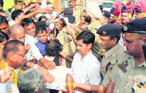 Police personnel distribute sweets among pilgrims, who arrived in Jammu on Monday