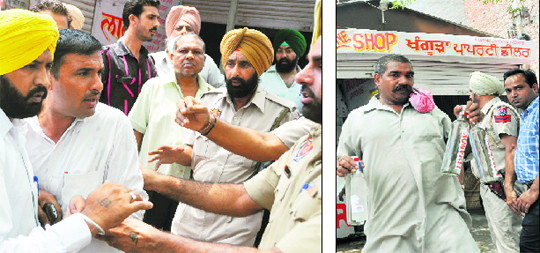 People argue with police officials during a demolition drive; and (right) workers take out liquor bottles from the vend that was razed by the municipal corporation in Ludhiana on Monday. 