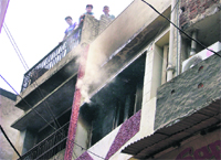 A shop catches fire as bystanders watch smoke billow from it in Saban Bazaar, Ludhiana, on Monday
