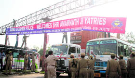 Police personnel put up a hoarding to welcome Amarnath yatris at the Kunjwani bypass road in Jammu.