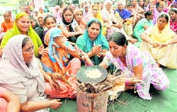 Women workers of the BSP light a 'chulha' to make 'chappatis' to protest against the recent hike in the prices of LPG and kerosene in Ludhiana